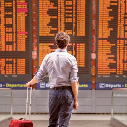 Persona mirando pantalla de vuelos en aeropuerto