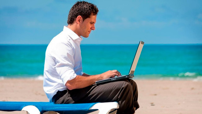 Hombre mirando computadora en la playa