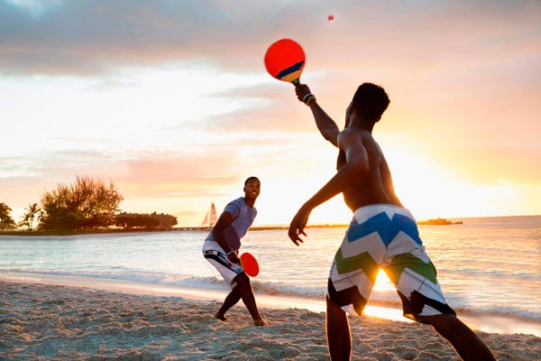 Niños jugando al ping pong en la playa